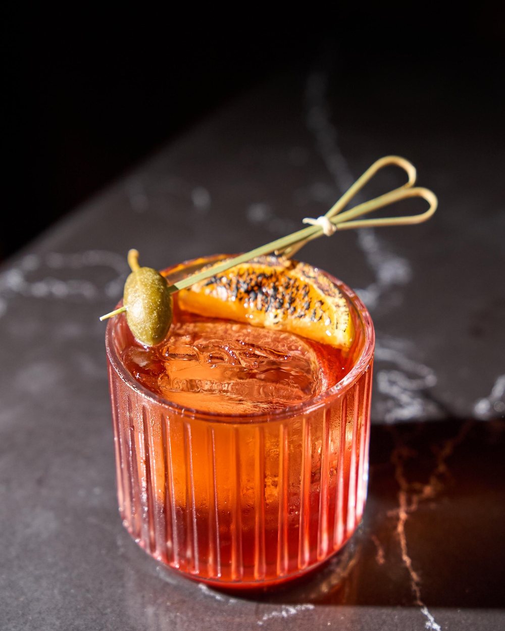 A negroni over ice with a charred orange wheel